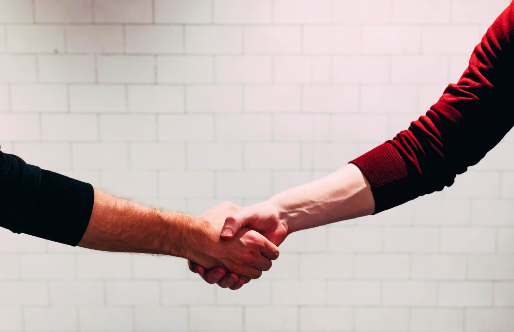 Image representing an agreement in an external patent acquisition, illustrating two parties shaking hands to symbolize the successful negotiation and finalization of the patent acquisition deal.